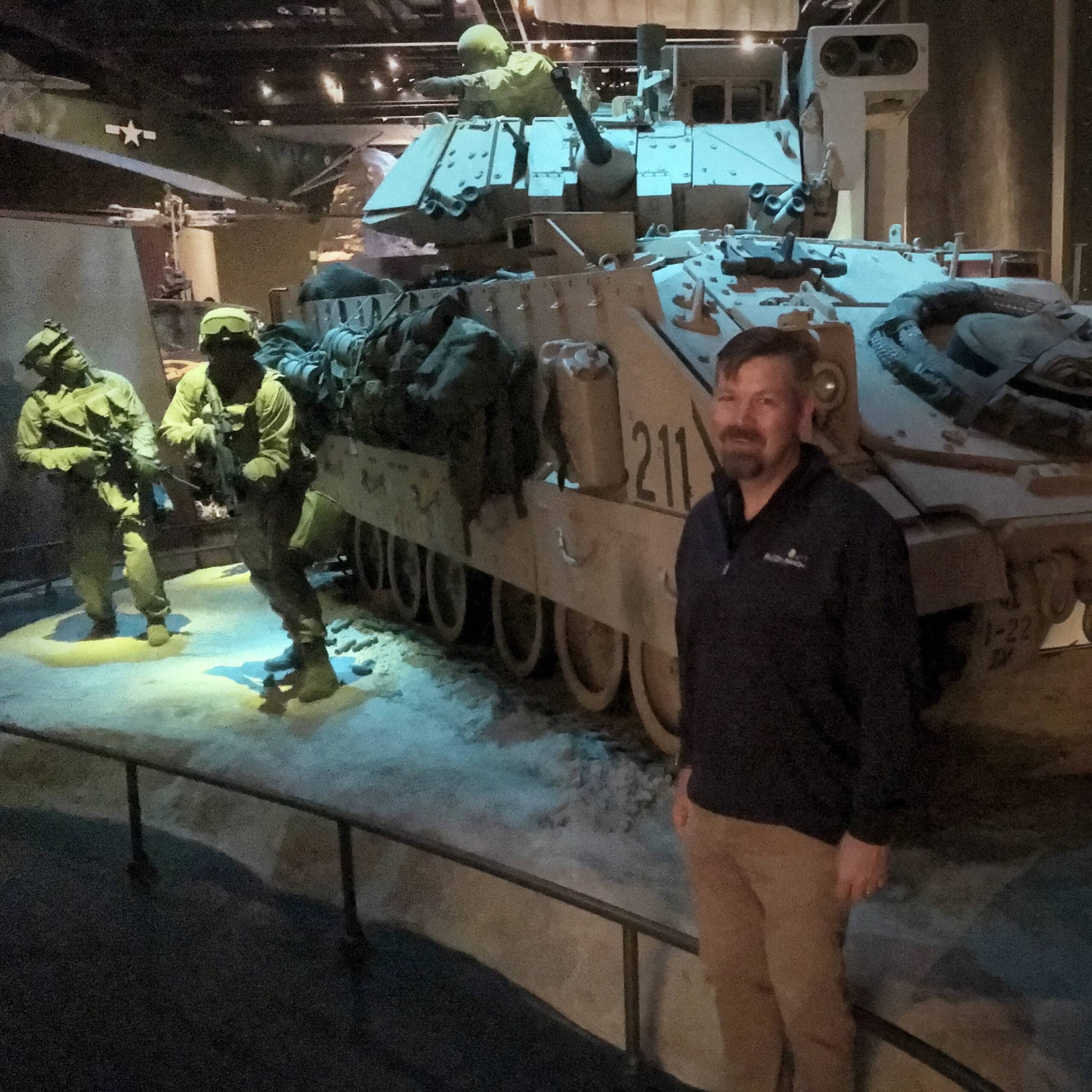 Nick DeVries posing in front of tank at Fort Benning's “Home of the Infantry”