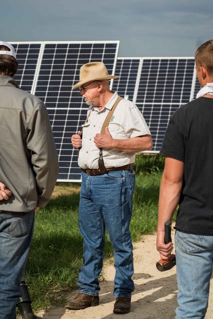 ranchers watch sheep exit trailer on regenerative energy farm